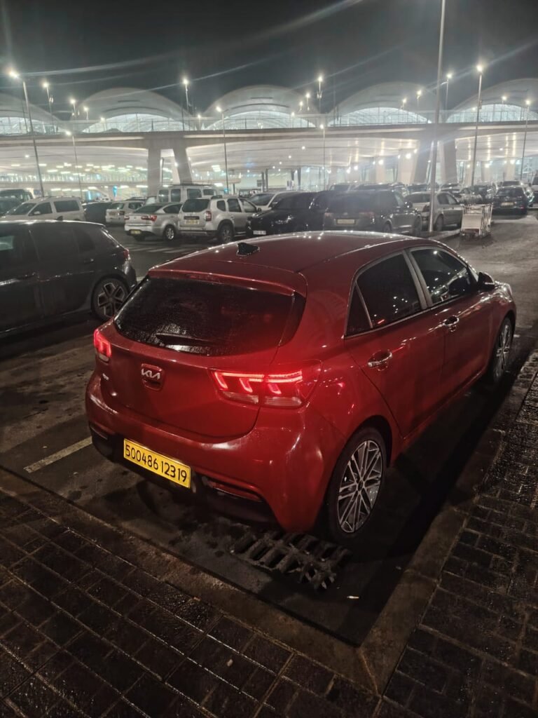 Kia Rio rouge en parking aéroport Algérie nuit – 2AY Location De Voitures Sétif