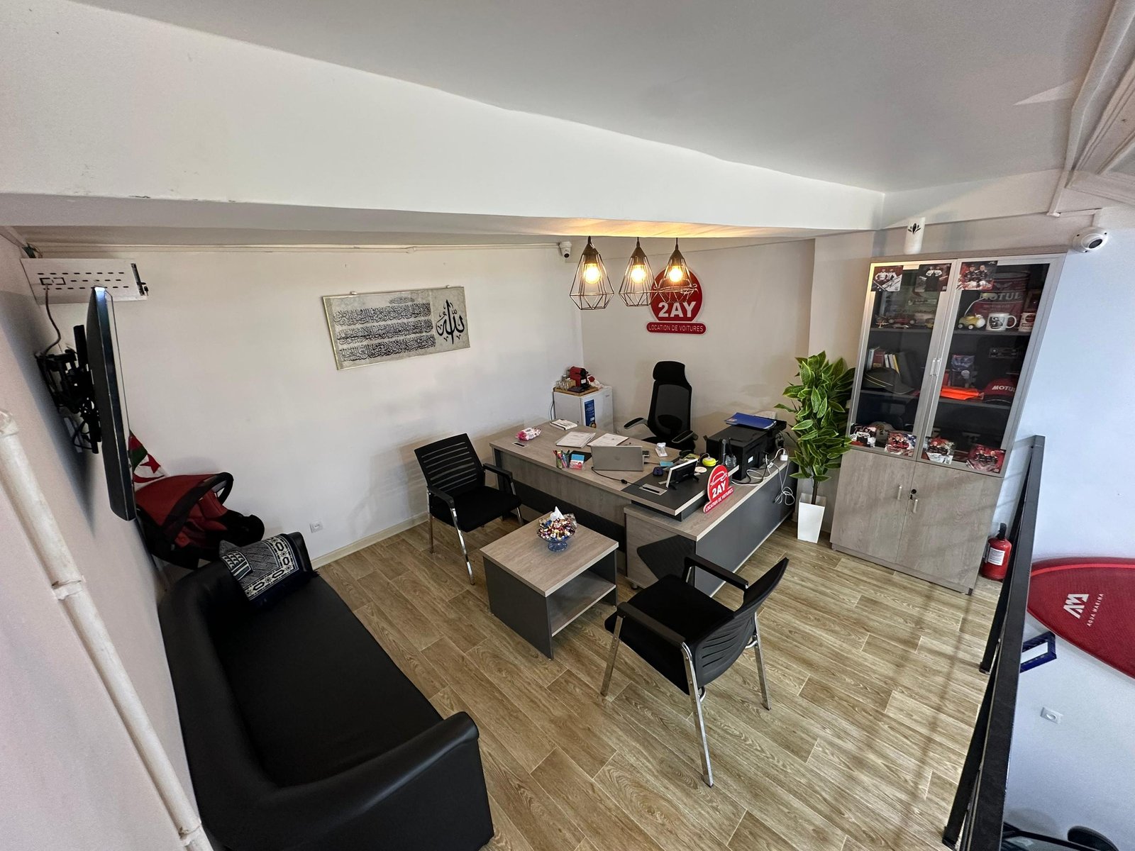 Bureau de l'agent chez 2AY Location De Voitures à Sétif — logo rouge 2AY sur le mur, espace de travail professionnel, agence de location de voiture basée à El-Maabouda Sétif