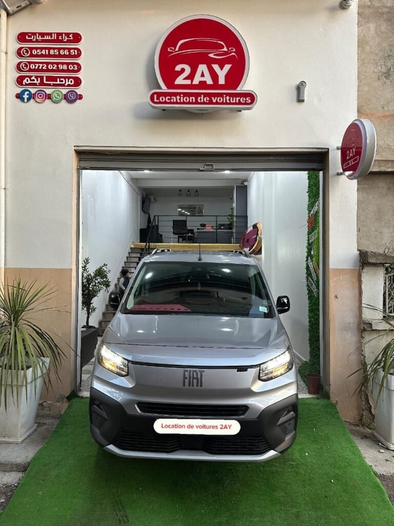Fiat Doblò Panorama 2025 gris face avant à l'entrée de l'agence 2AY Location Voiture Sétif