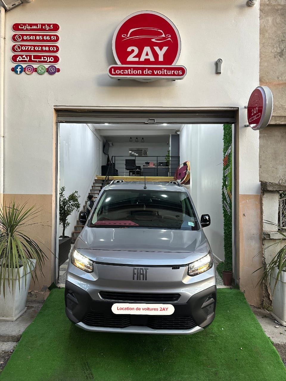 Fiat Doblò Panorama 2025 gris face avant à l'entrée de l'agence 2AY Location Voiture Sétif